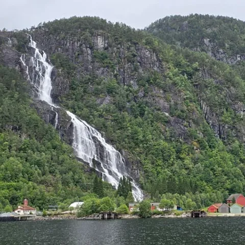 A waterfall falling to the fjord beside a small farm
