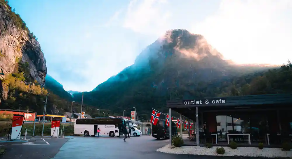 A coach parked outside a roadside cafe under Norwegian flags
