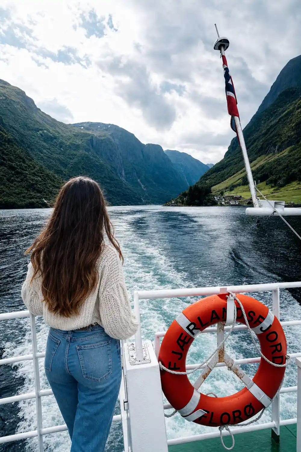 The Norwegian flag at the stern of the boat above the wake