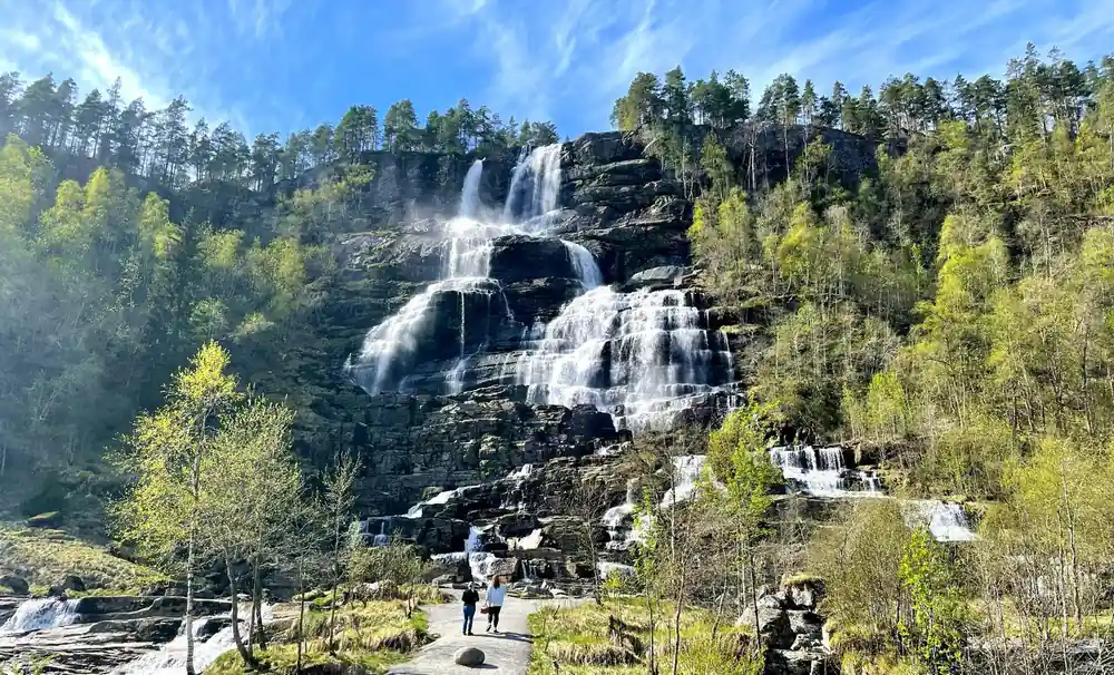 Tvindefossen falling in many strands with people on the path below