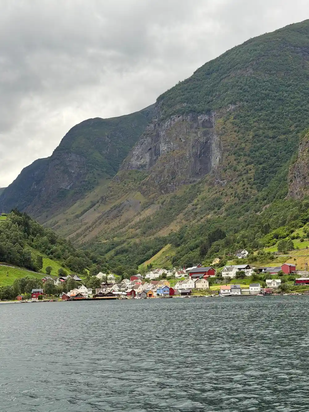 A village strung along the shore under a striped mountain wall