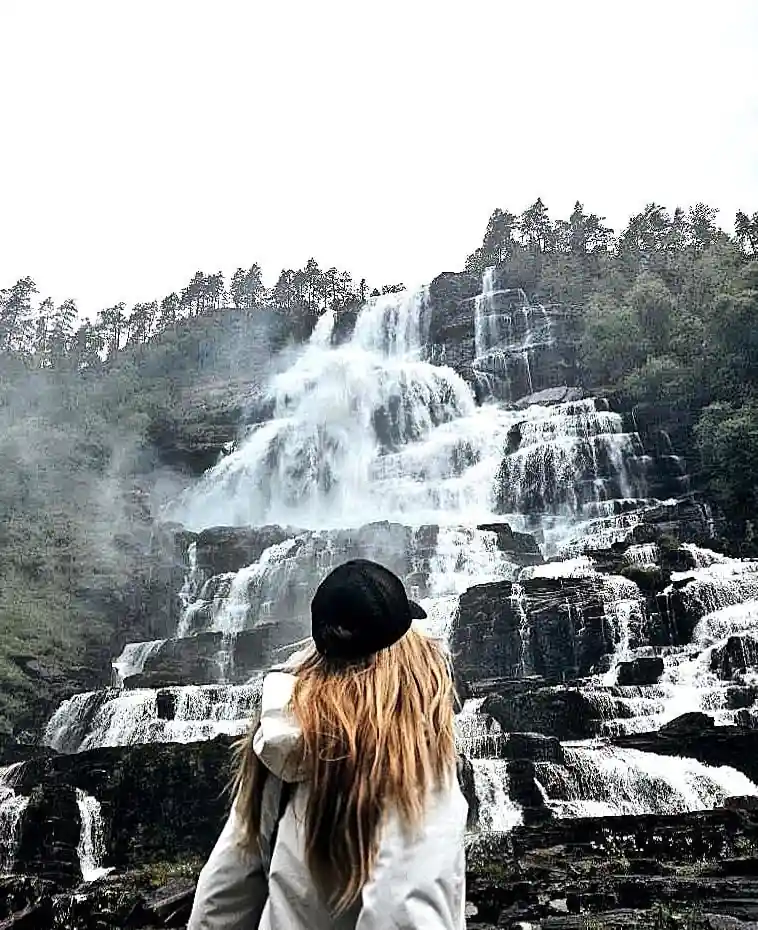 A visitor looking up at Tvindefossen from the path