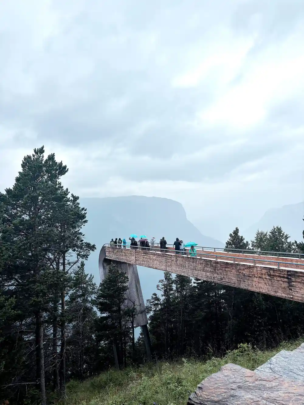 Visitors standing along the platform in cloud above the fjord