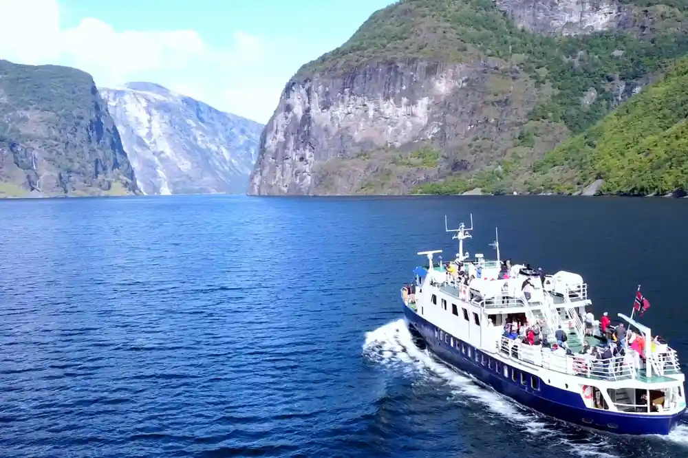 A white fjord cruise vessel under way on deep blue water